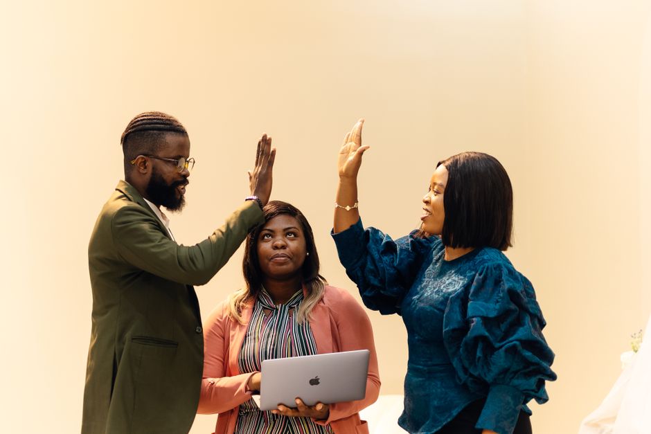 Three colleagues celebrating a successful tender win with a high five in an office setting